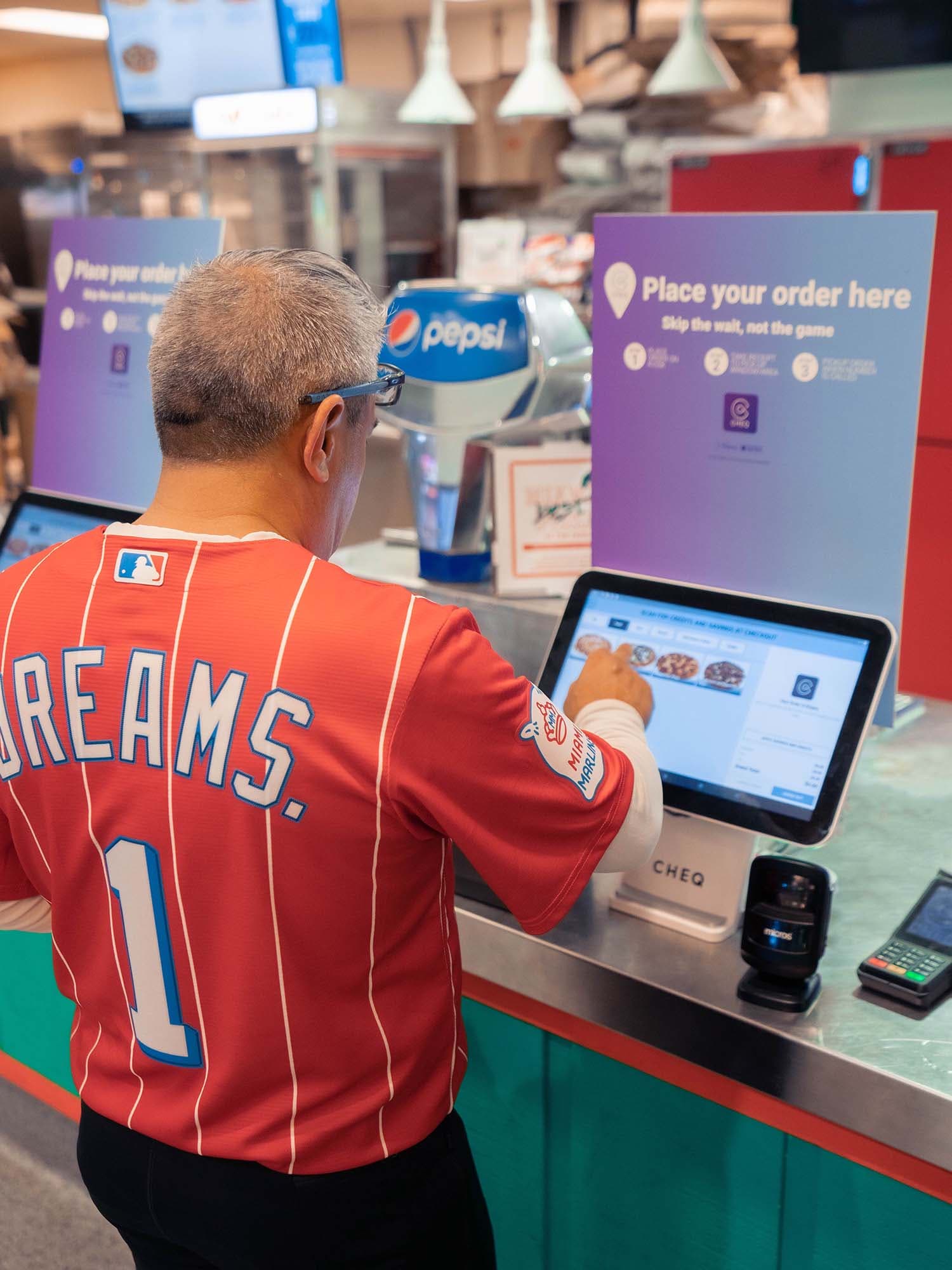 Man with “Dreams. 1” jersey using the CHEQ kiosk.